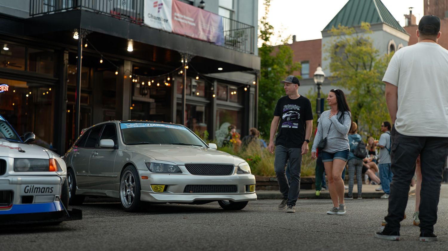 Urban panorama showing pedestrians and vehicles on a brick-lined street.