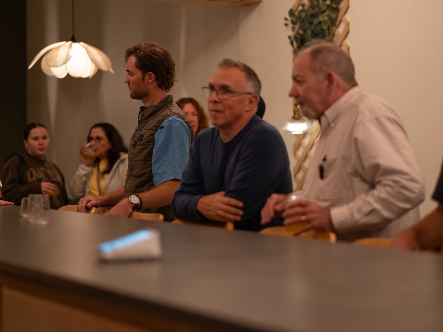 People gathered around a table in a dimly lit room having a conversation during a social gathering.