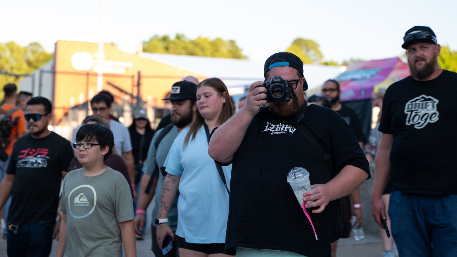 Large group of attendees walking through an outdoor venue during daytime.