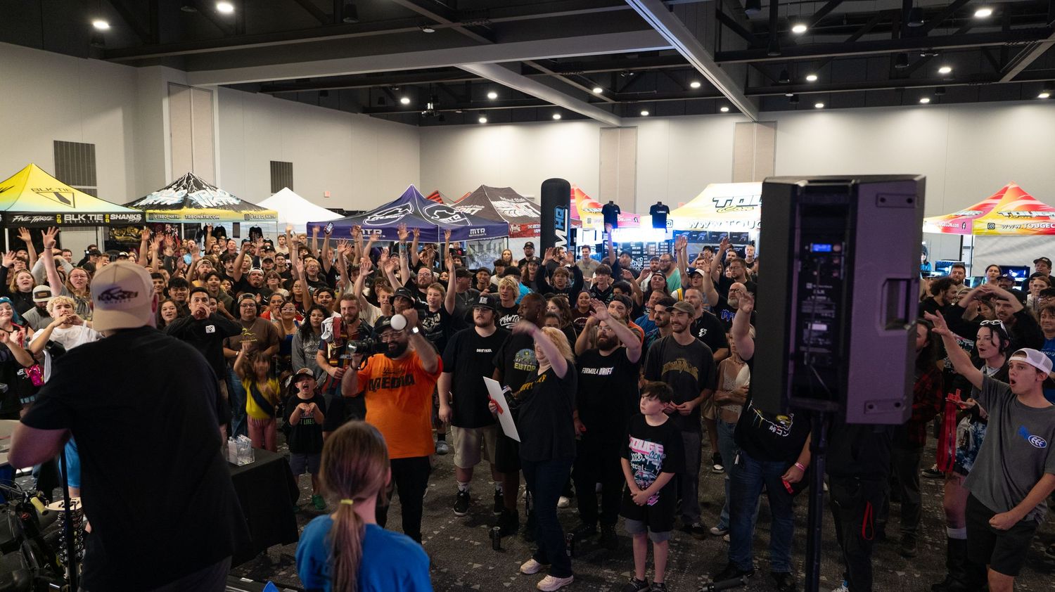Wide-angle shot of convention center filled with attendees and gaming displays.