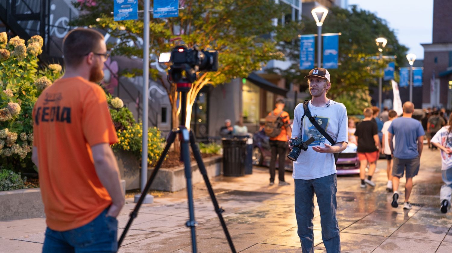 Camera equipment and filming setup on a busy urban street during an outdoor event.