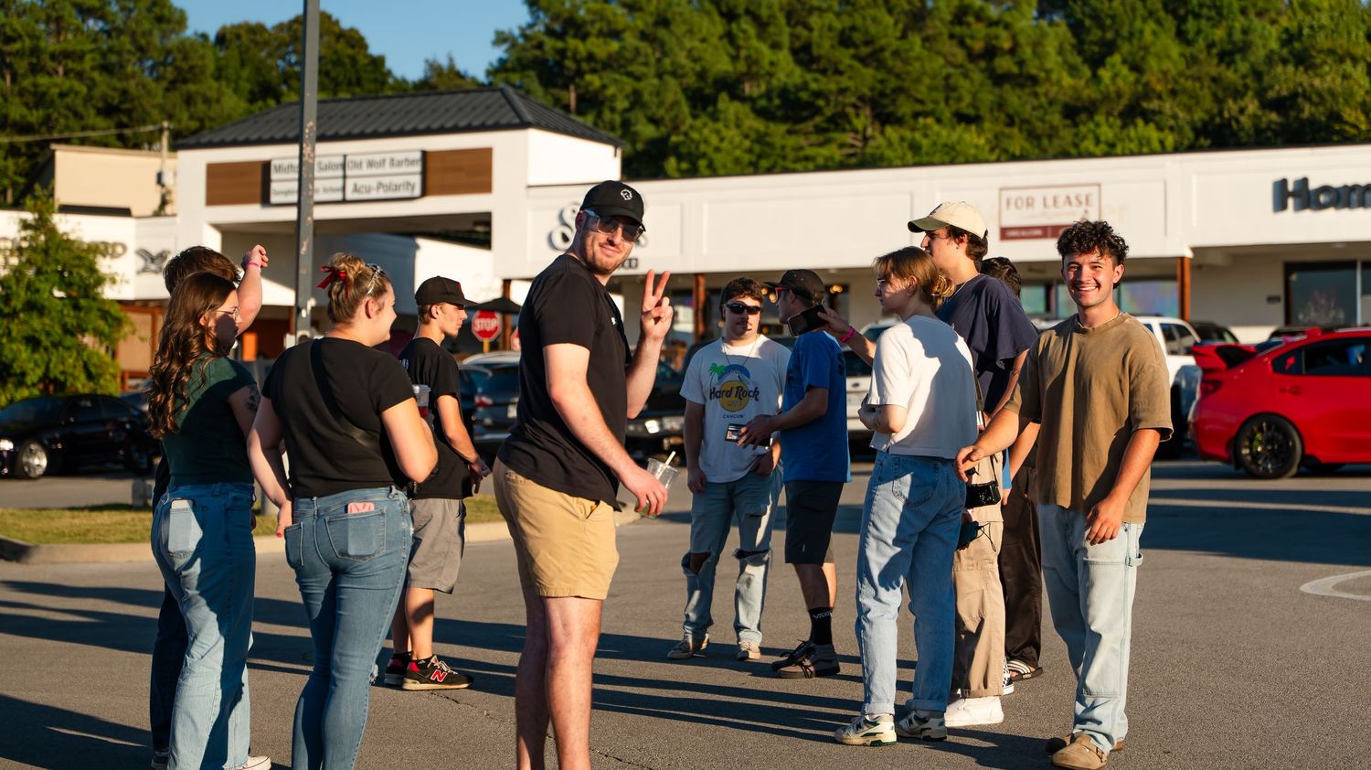 Car enthusiasts gathered at an outdoor auto show viewing various vehicles.