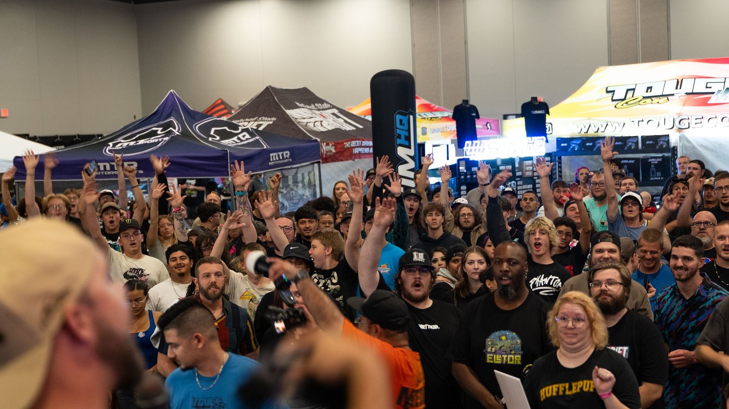 Panoramic view of gaming convention floor with promotional banners and dense crowd.