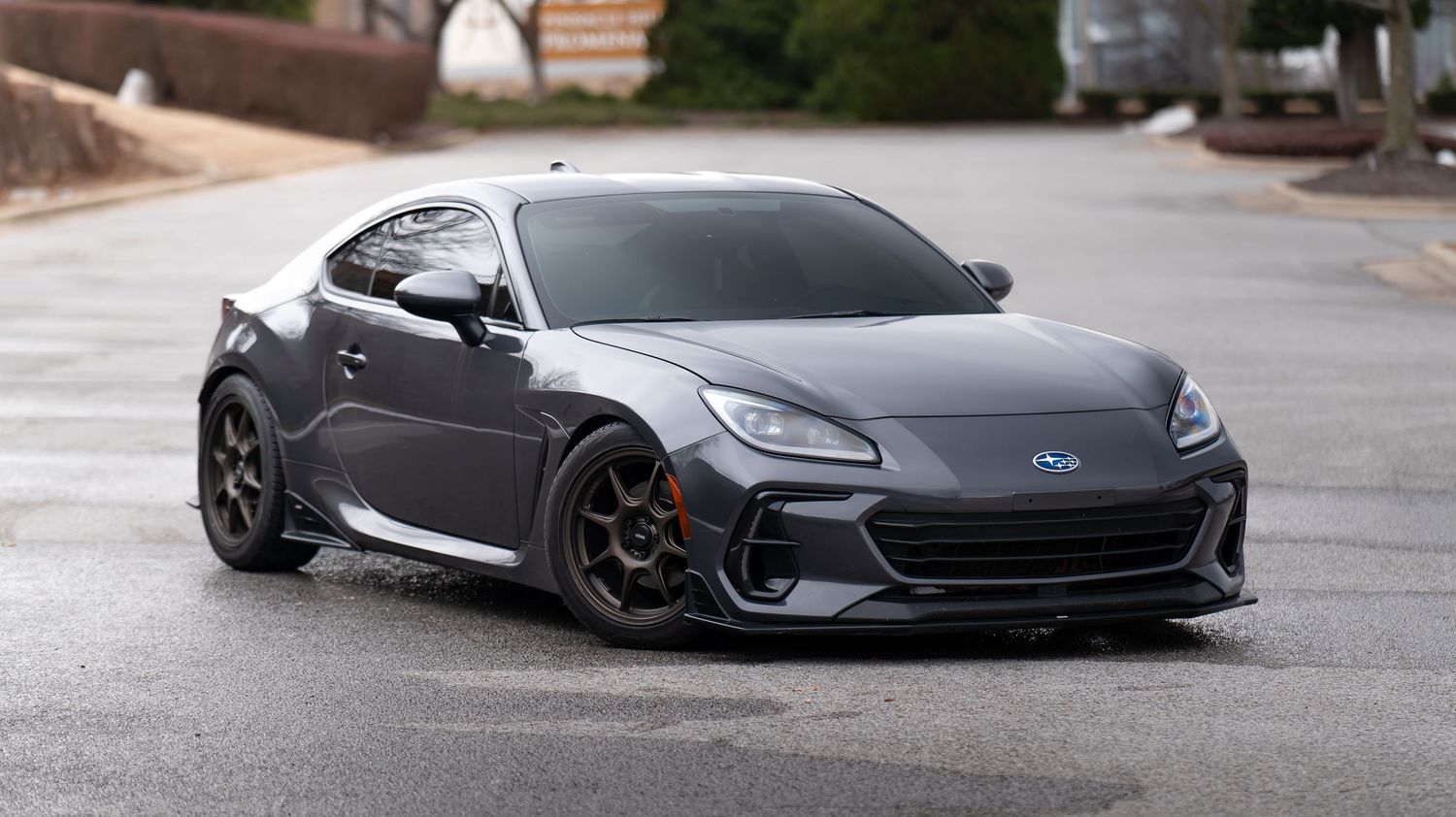 Side profile of a modified Subaru BRZ with custom body kit and black wheels.