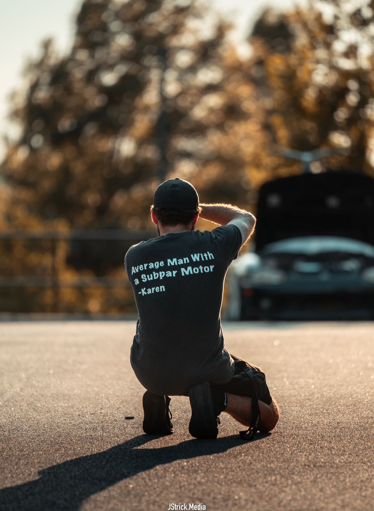 People in branded clothing photographed at sunset in various crouching poses near parked vehicles.