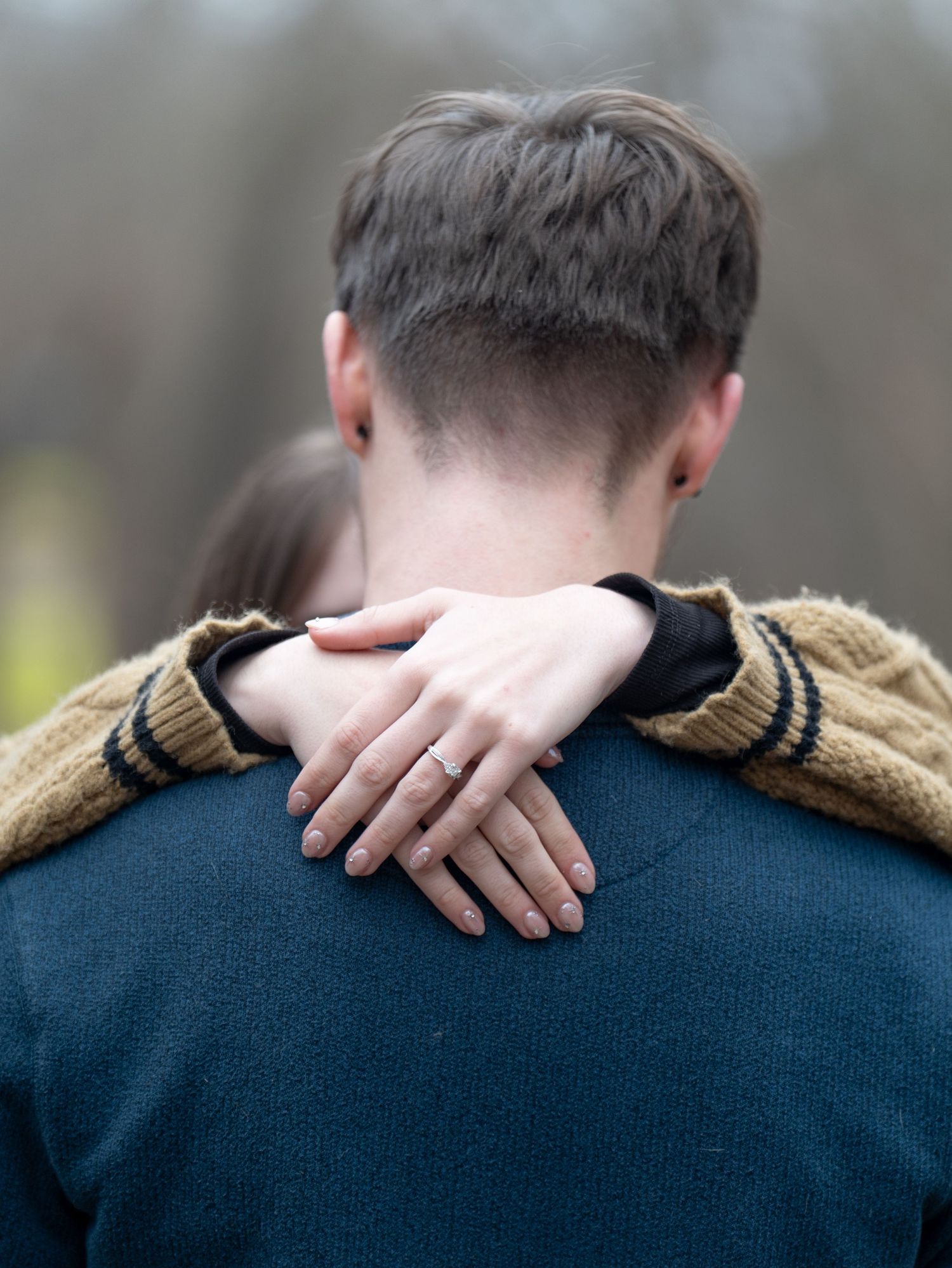 A hand gently rests on a shoulder wearing a navy sweater with tan epaulettes in a sequence of similar poses.