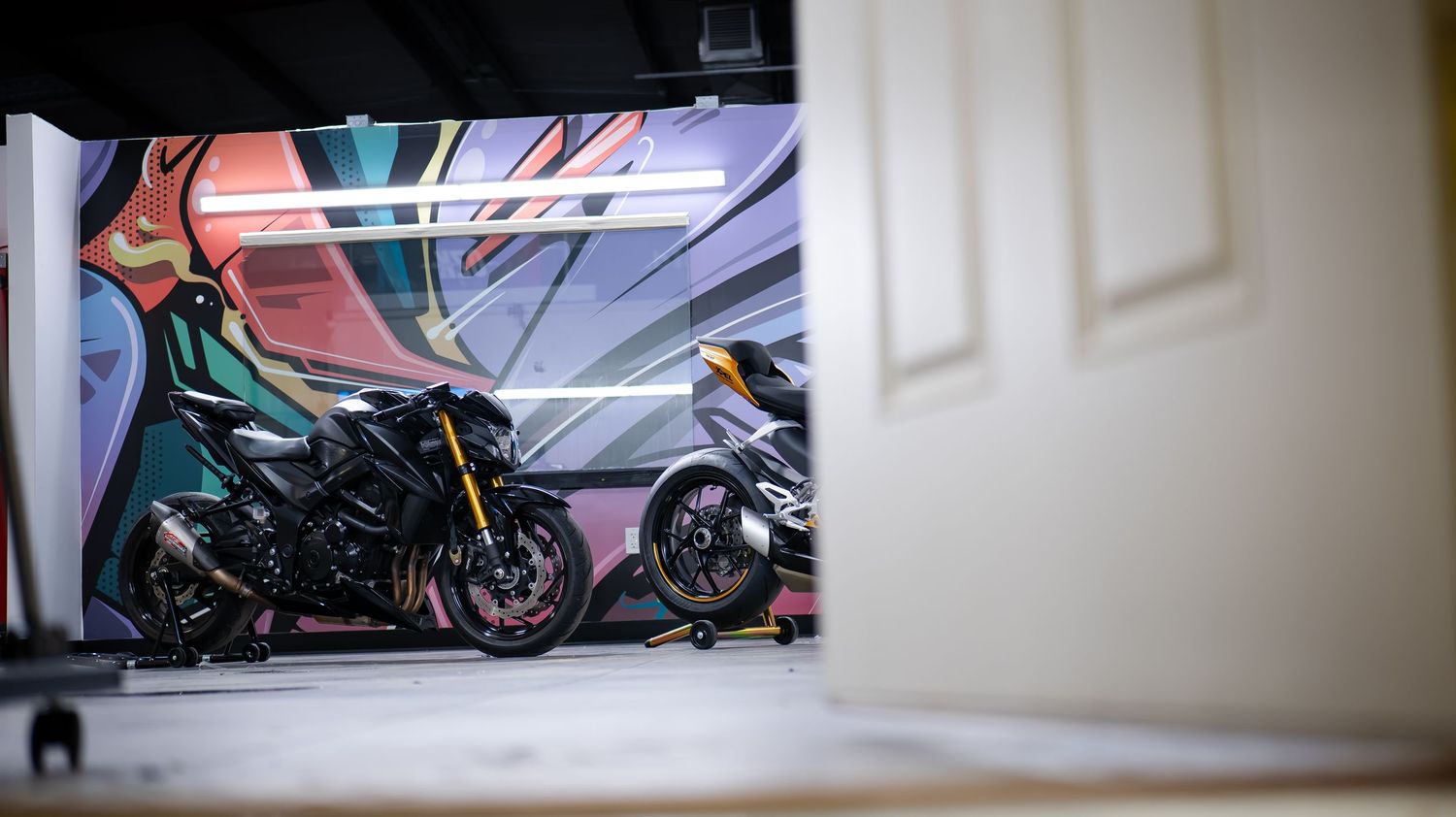Panoramic view of a motorcycle workshop with white walls and lighting.