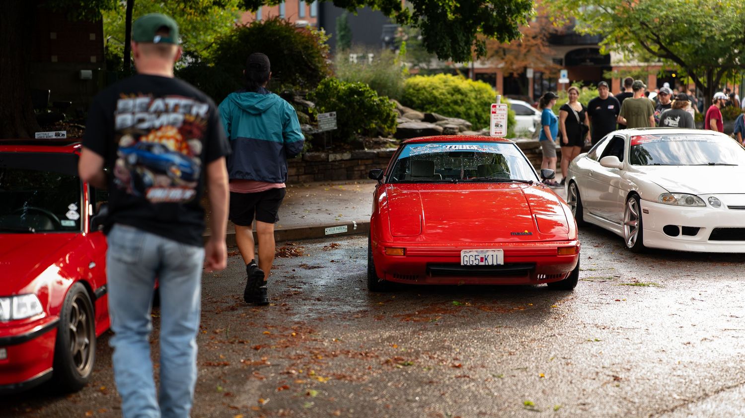 Classic and modified cars displayed at street auto show with spectators.