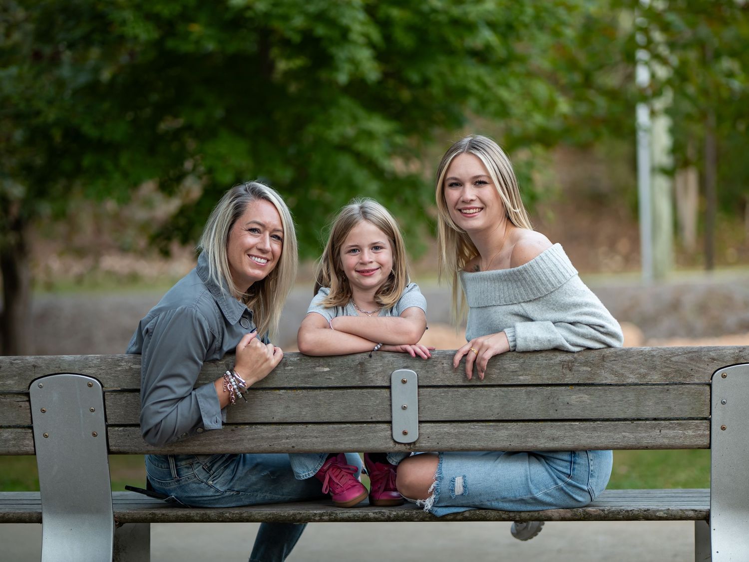 People sitting on a rustic wooden bench in a natural outdoor setting.