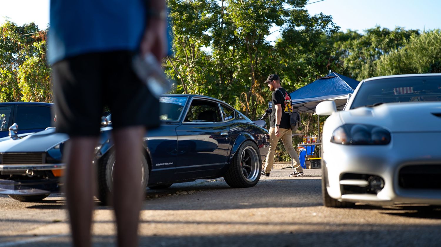 Low perspective shot of cars parked in a line with sunlight filtering through trees.