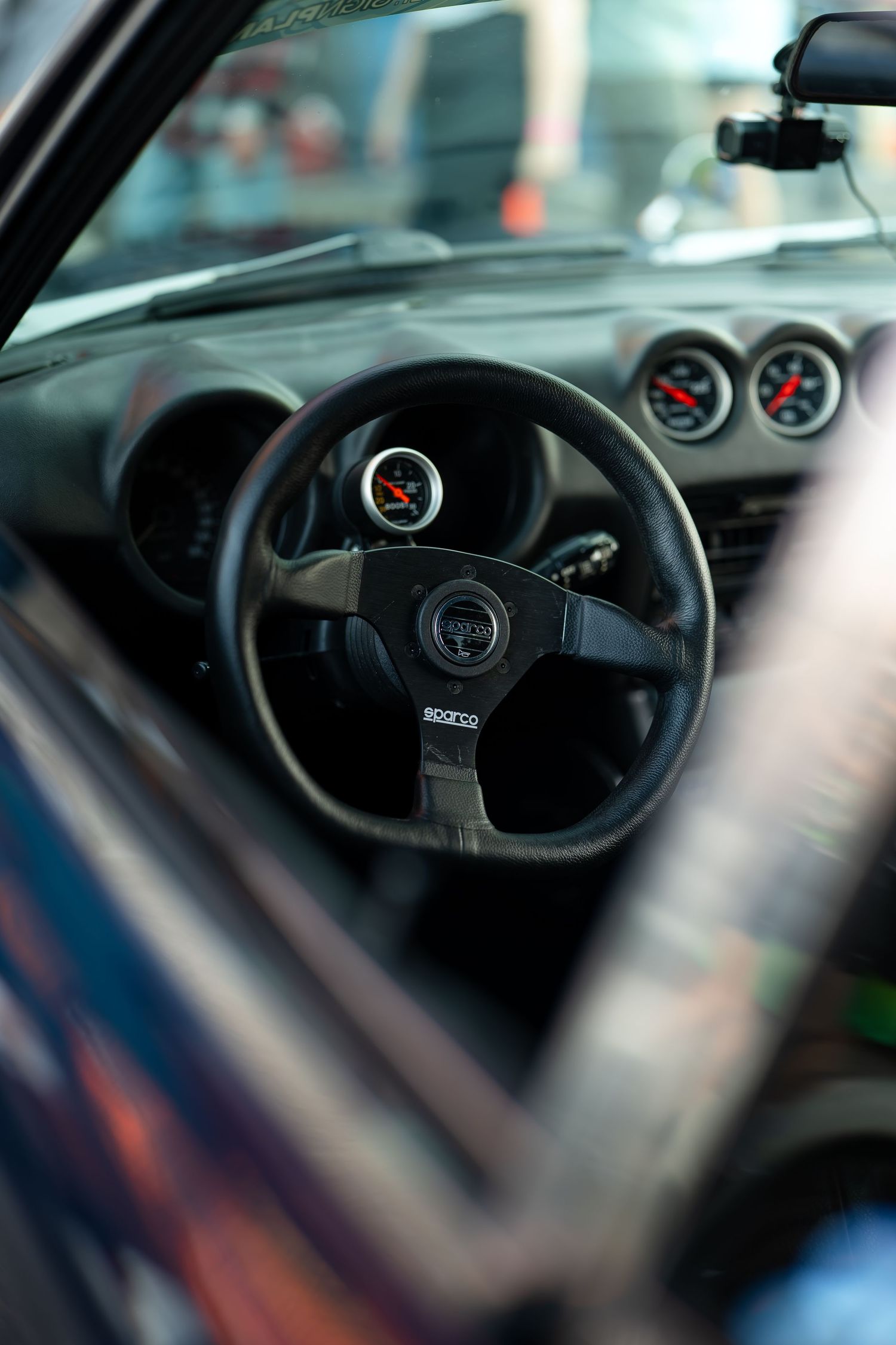 Close-up shots of black steering wheels in modern sports cars showing performance gauges.