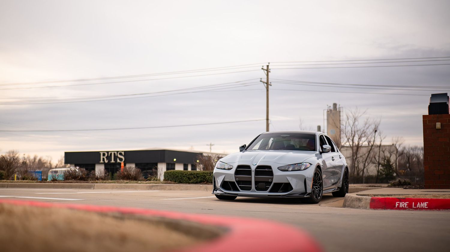 Panoramic view of luxury cars parked in front of modern buildings at sunset.
