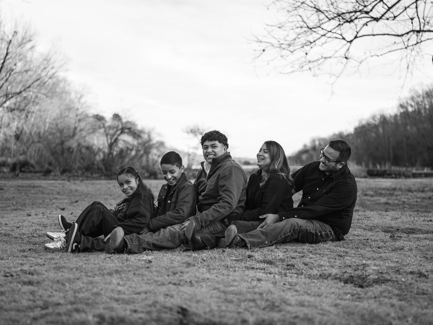 A series of black and white photos showing people lying down in a grassy field during daytime.