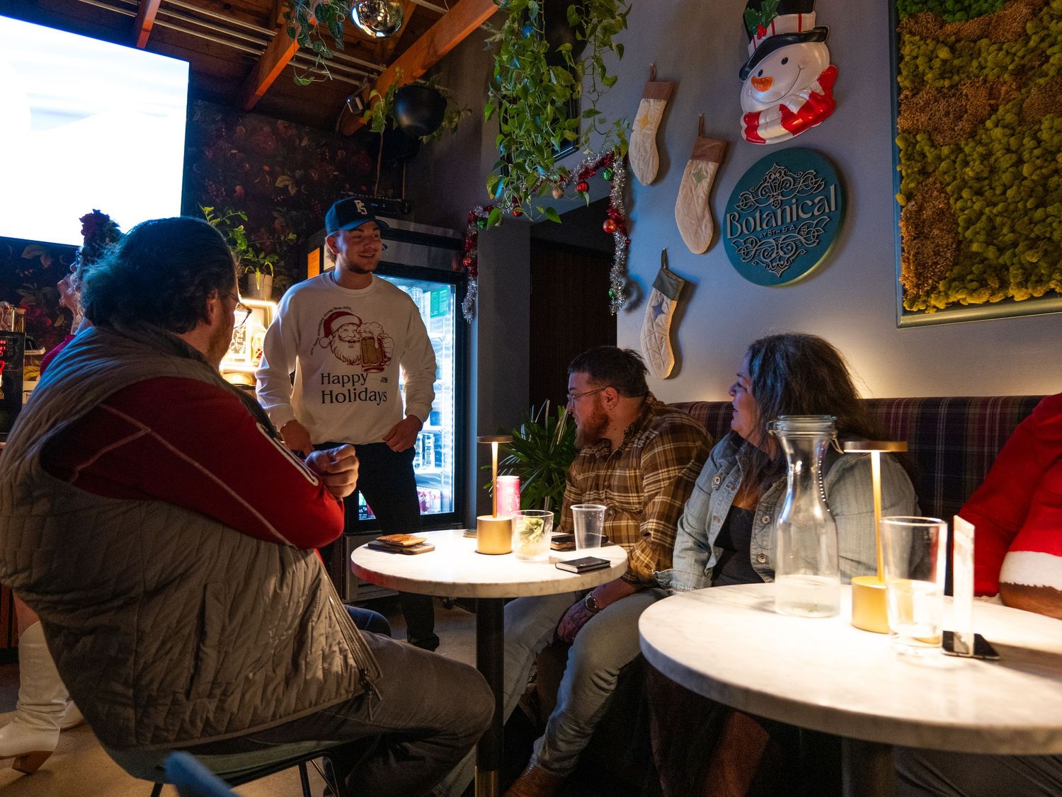 People gather at illuminated tables in a dimly lit restaurant or bar setting creating an intimate atmosphere.