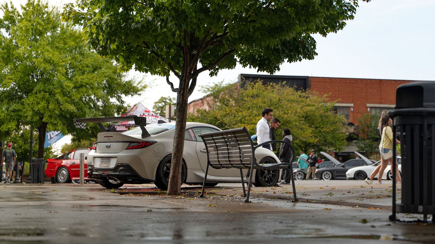 Tree-lined street panorama with parked vehicles and buildings visible.