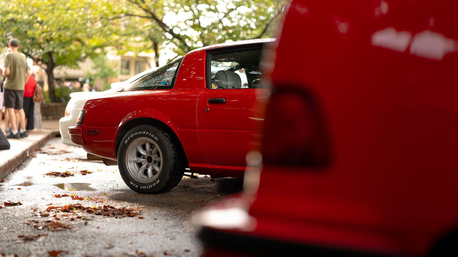 Red sports cars lined up at outdoor automotive event.