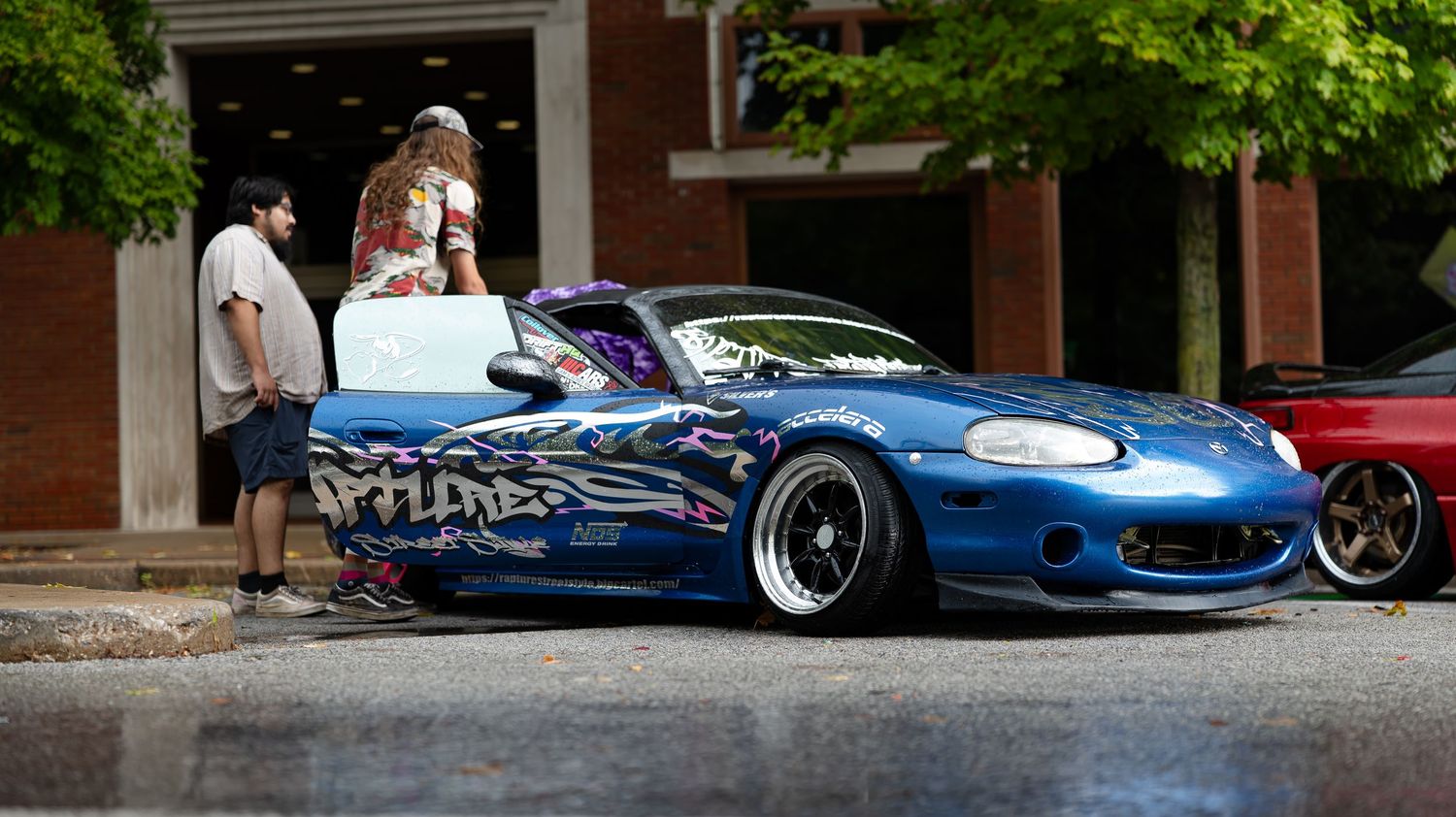 Custom sports cars with aftermarket modifications displayed at an outdoor event.