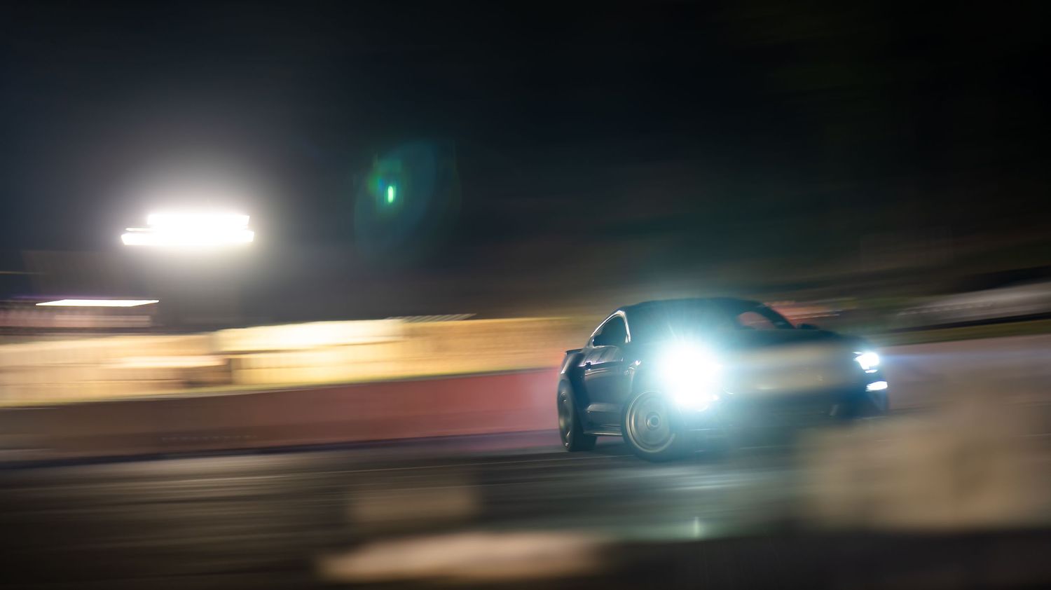 Time lapse of car lights streaking across dark background at night.