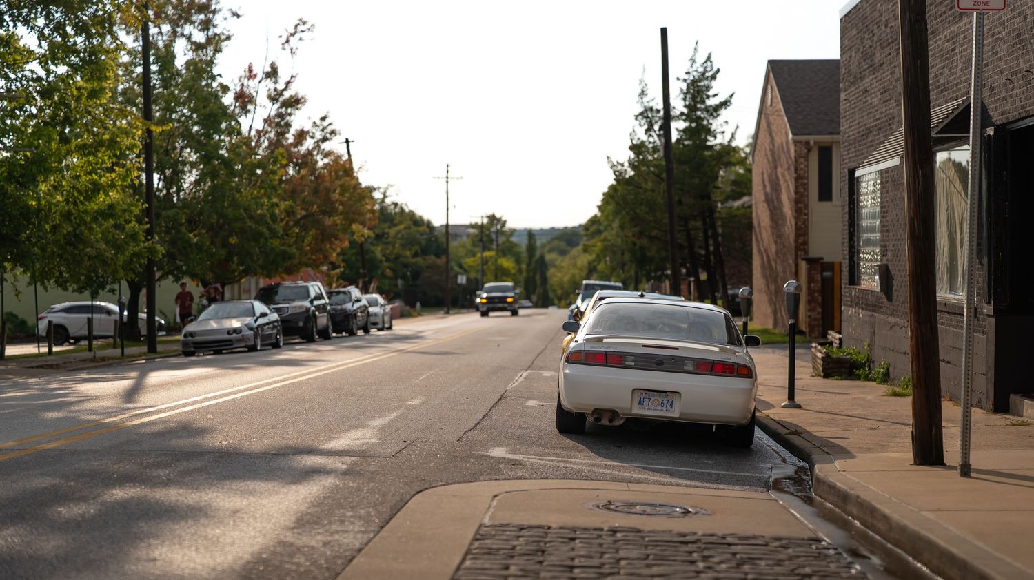 Wide angle view of a quiet suburban street with trees and buildings.