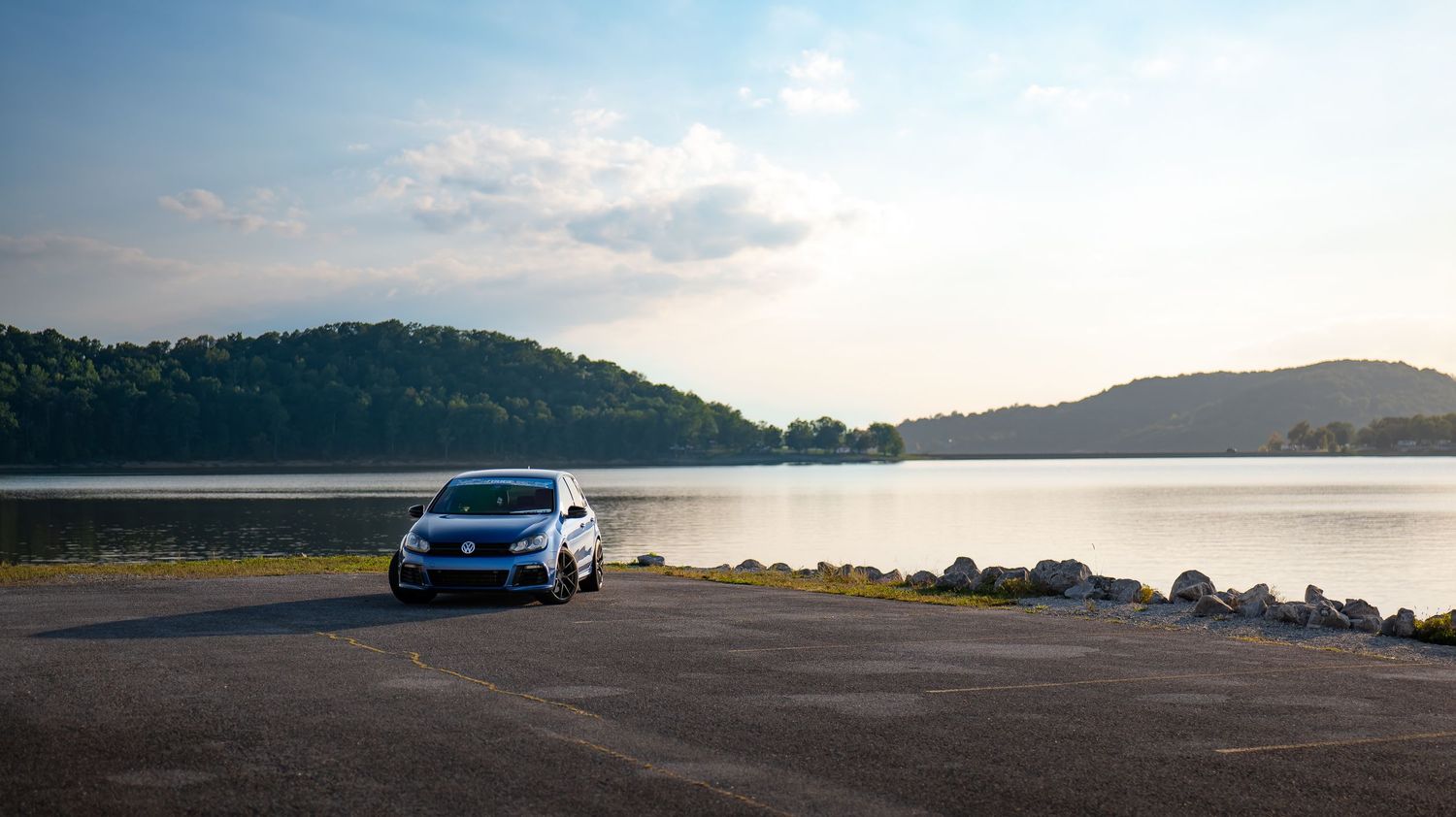 Wide angle view of cars parked along a scenic overlook with mountains in the distance.