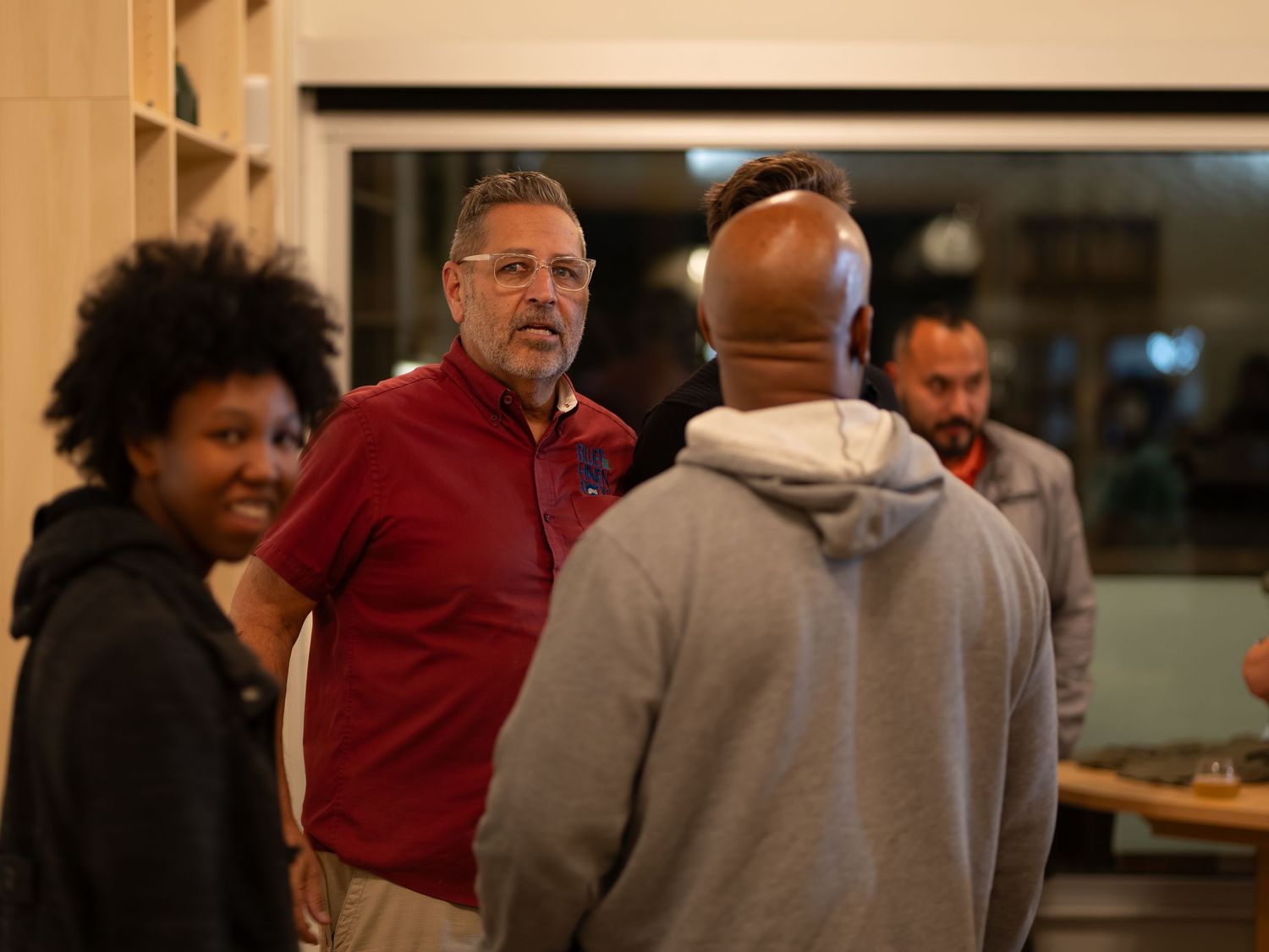 A group of people gathered in conversation at an indoor event or gathering space.