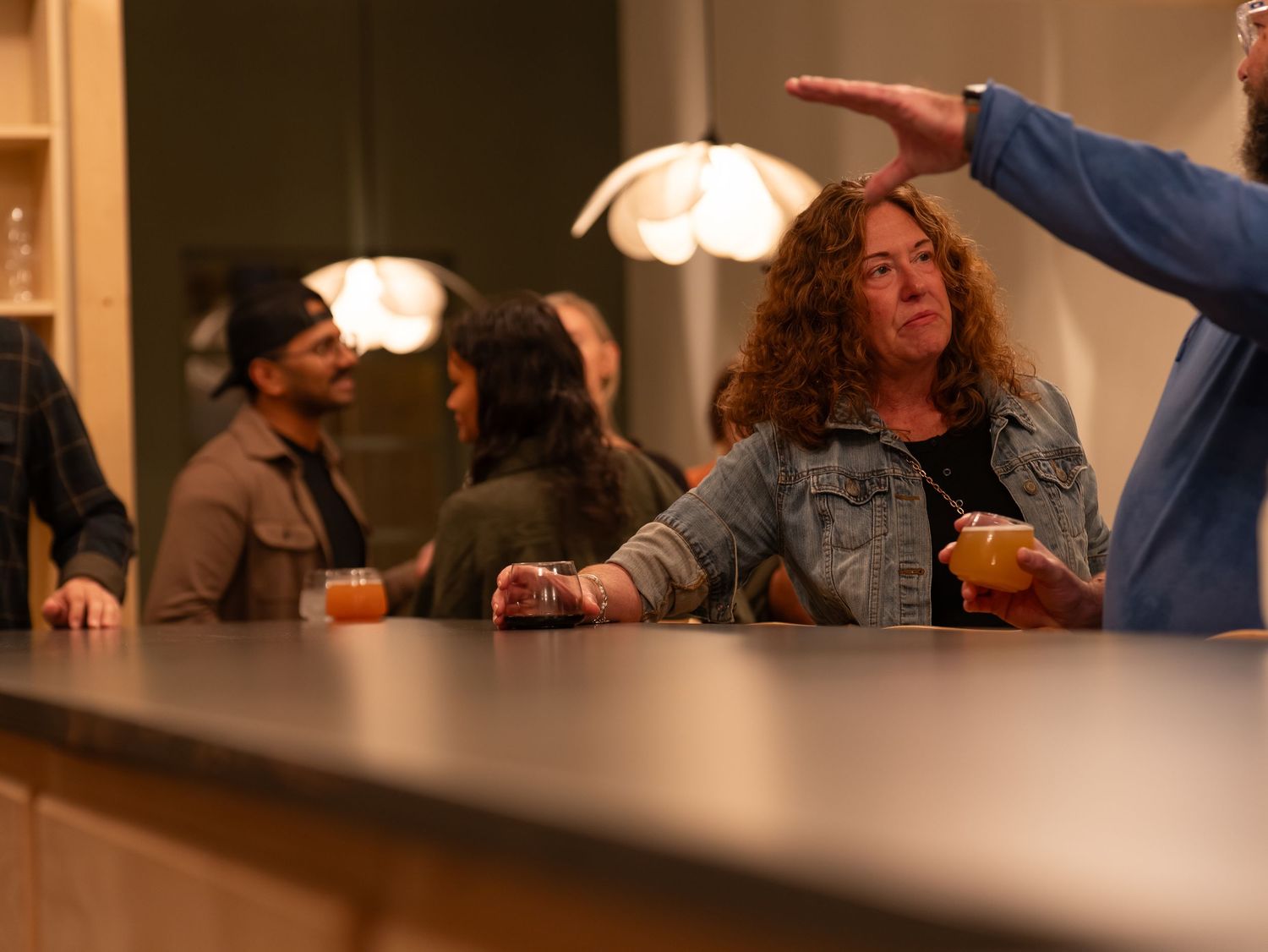 People sitting at a bar counter with drinks and food in a dimly lit restaurant setting.