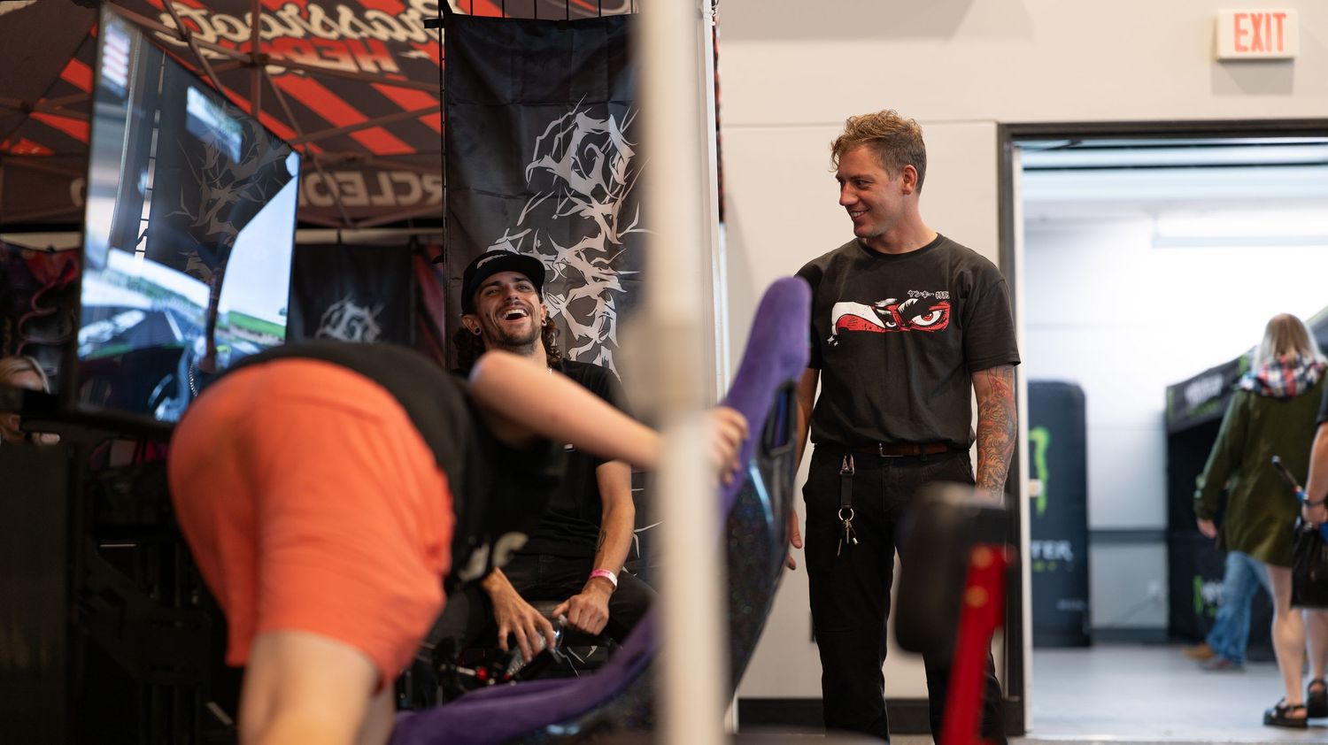 Indoor automotive event space with vendor booths and enthusiasts browsing displays.