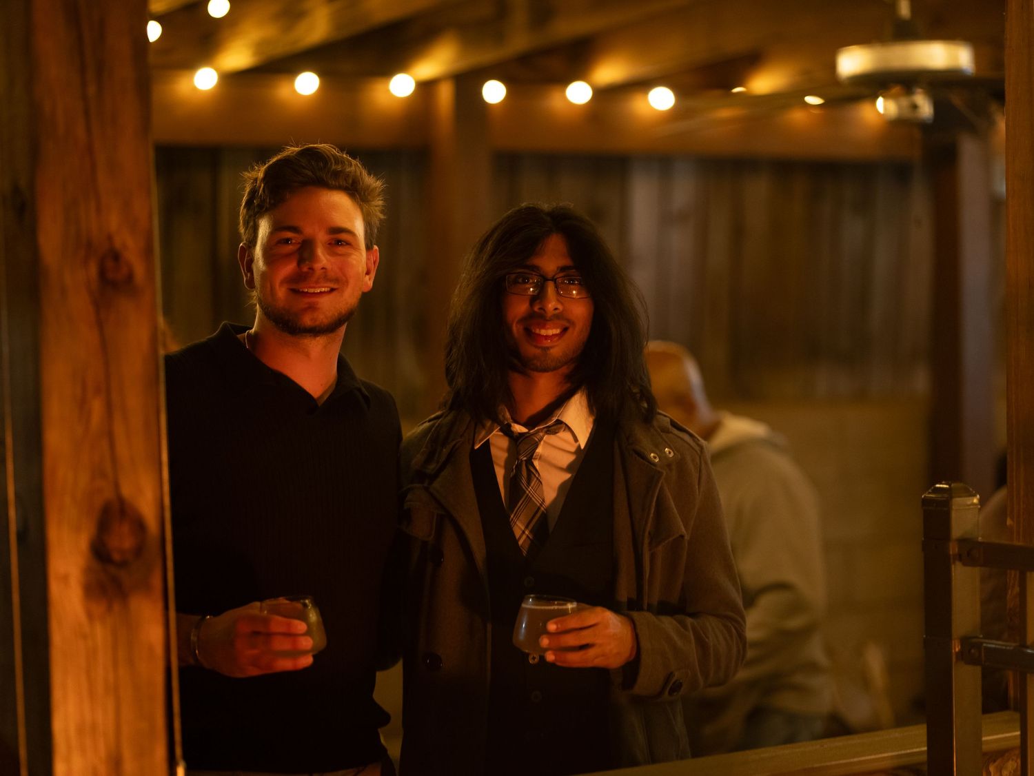 People enjoying drinks and conversation at a rustic wooden bar with warm lighting and cozy ambiance.
