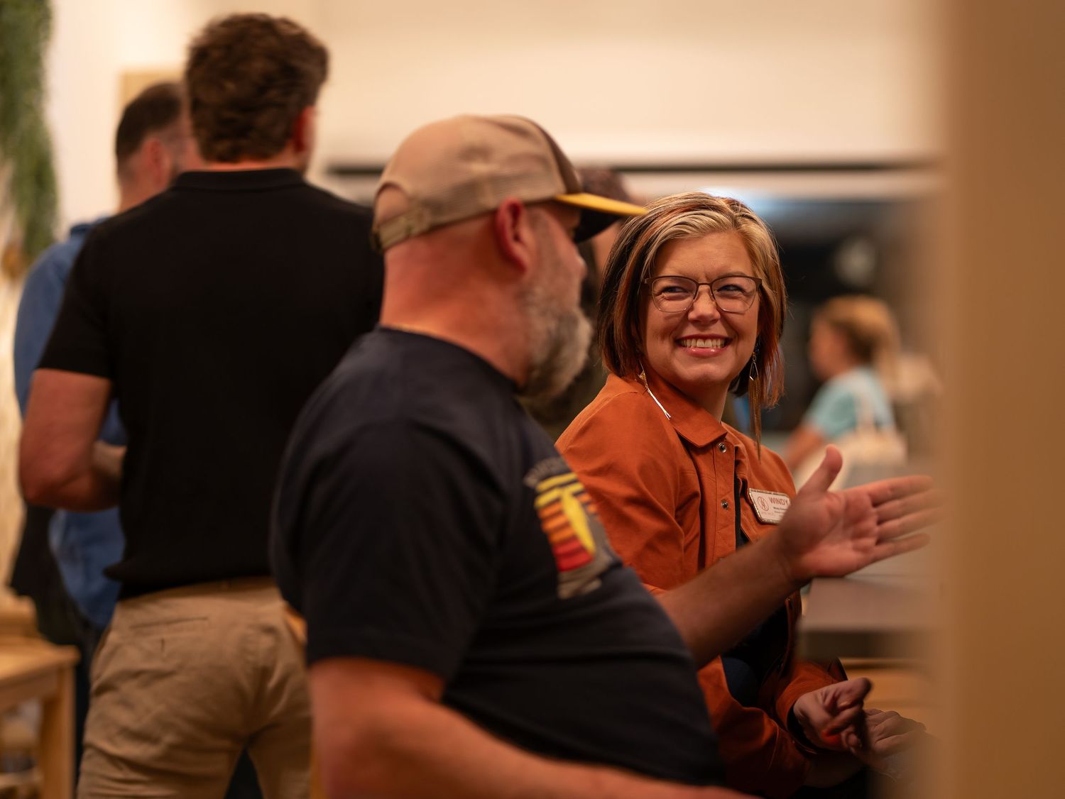 People laughing and socializing at a casual gathering or event in an indoor setting.
