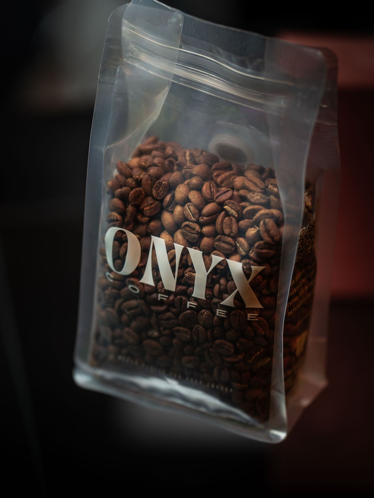 Close-up sequence of coffee beans in a glass jar labeled 'ONYX' with varying focus and angles in dark lighting.