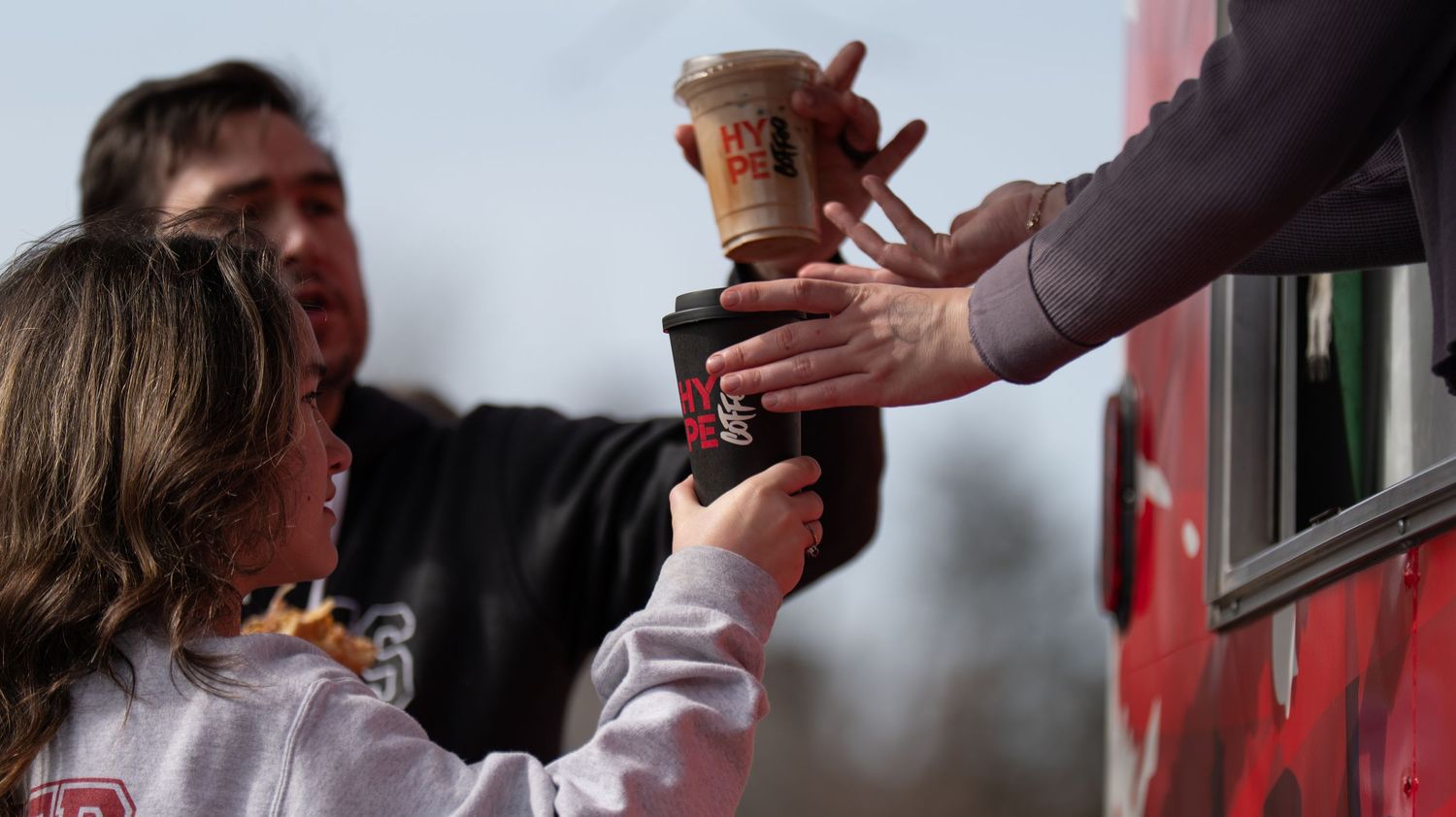 Group of customers receiving drinks from a service window.