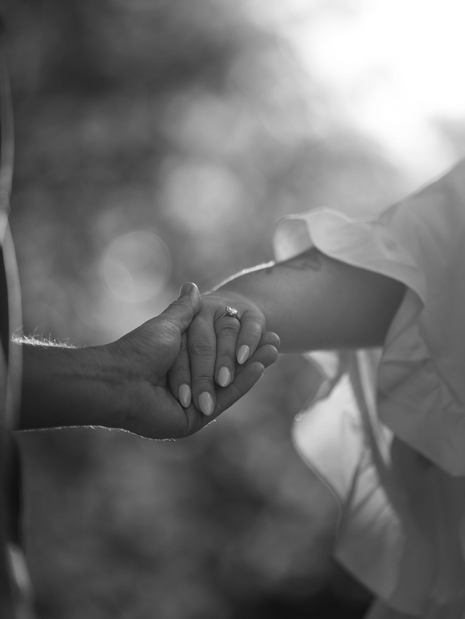 Black and white close-up photo of hands holding a small object in soft focus with dreamy bokeh effect.