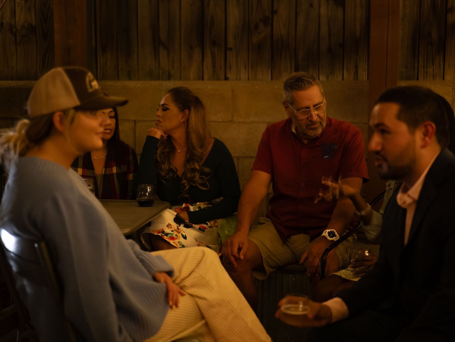 People gathered around tables in a dimly lit restaurant or bar setting enjoying drinks and conversation.