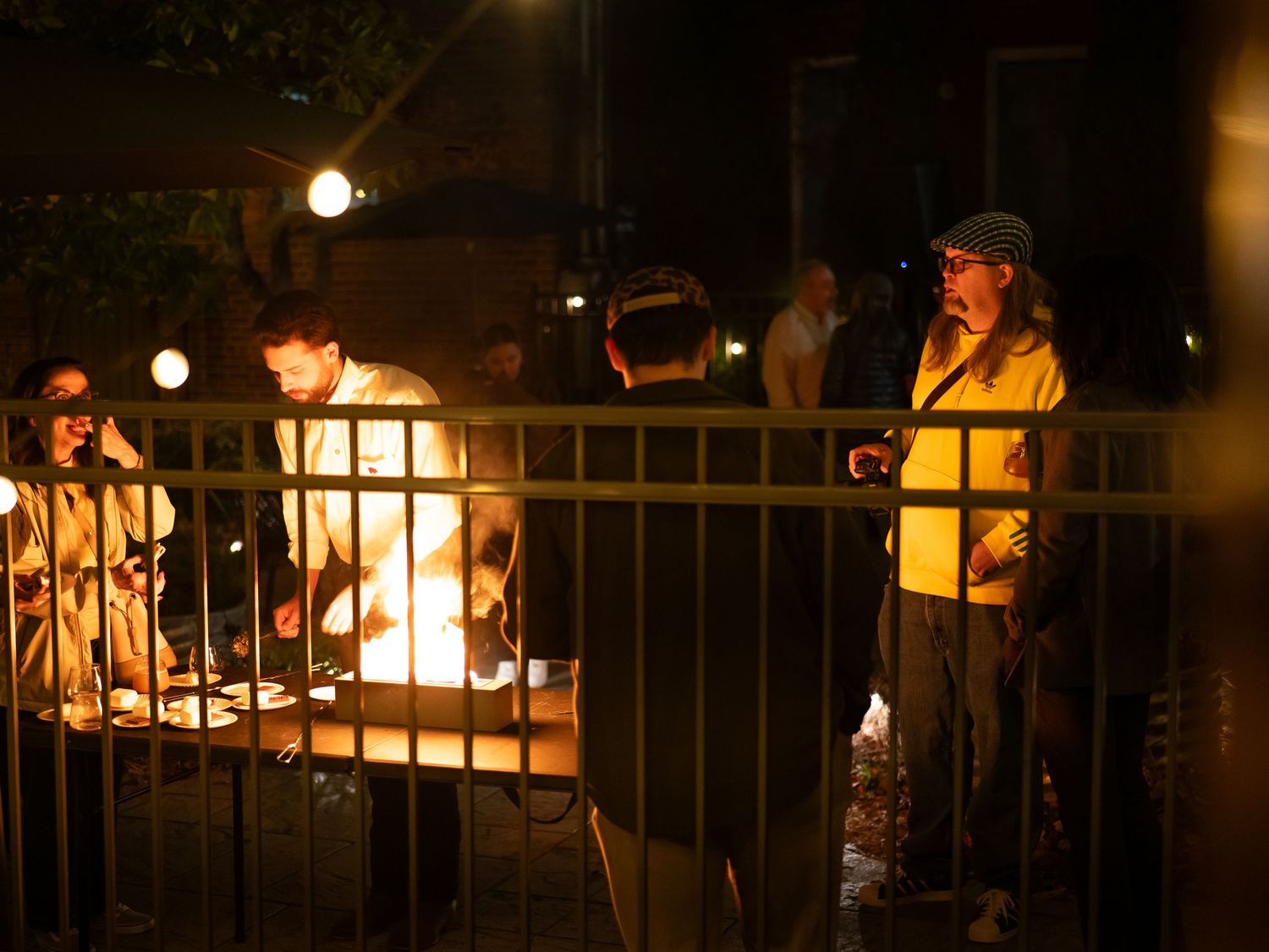 A row of illuminated outdoor lamps and railings create a warm ambiance at night.