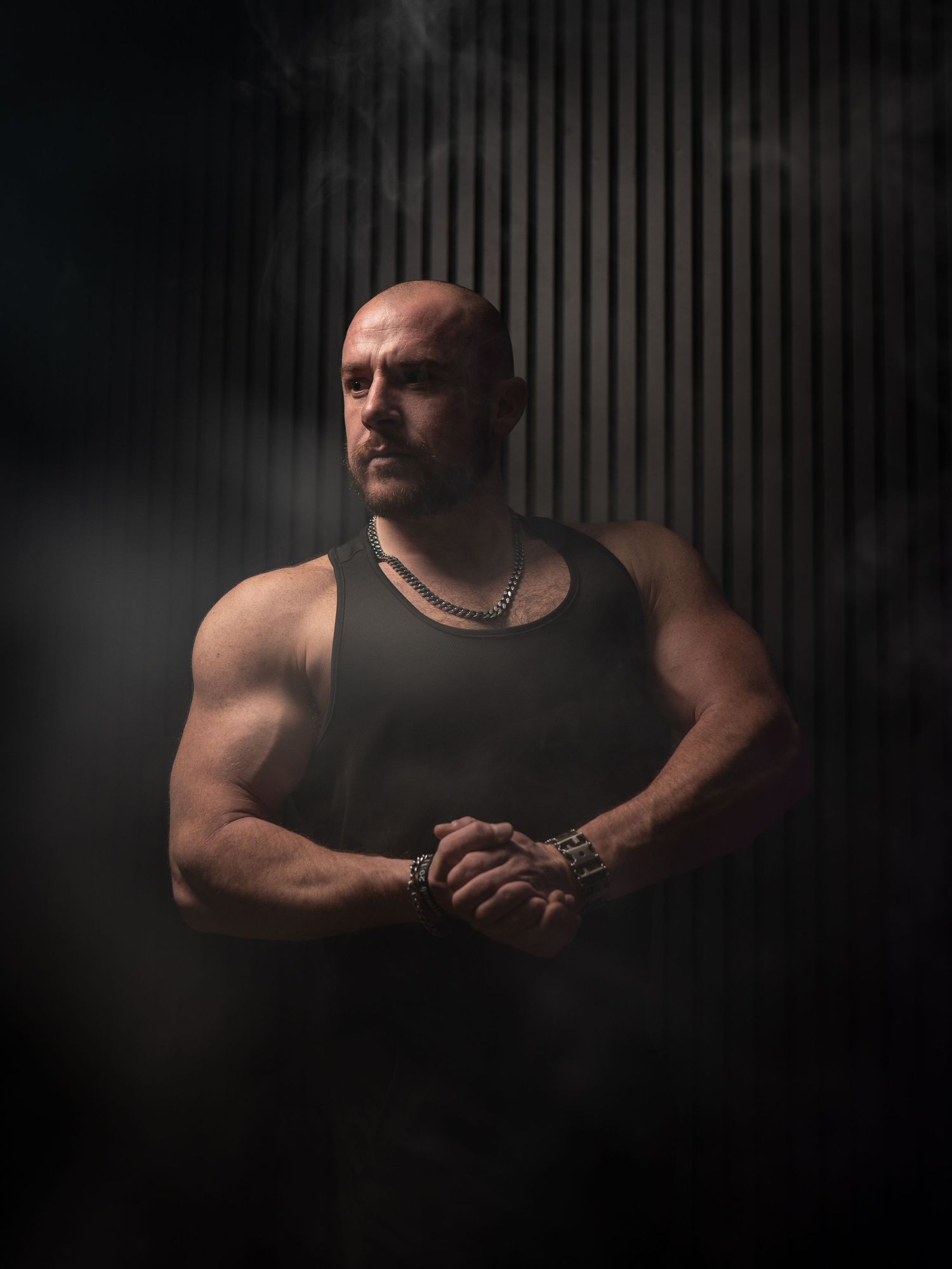Dramatic black and white portrait series showing a muscular figure in a tank top against a dark background.