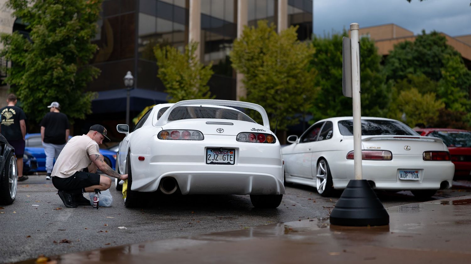 Row of parked cars at an outdoor auto show with cloudy skies overhead.