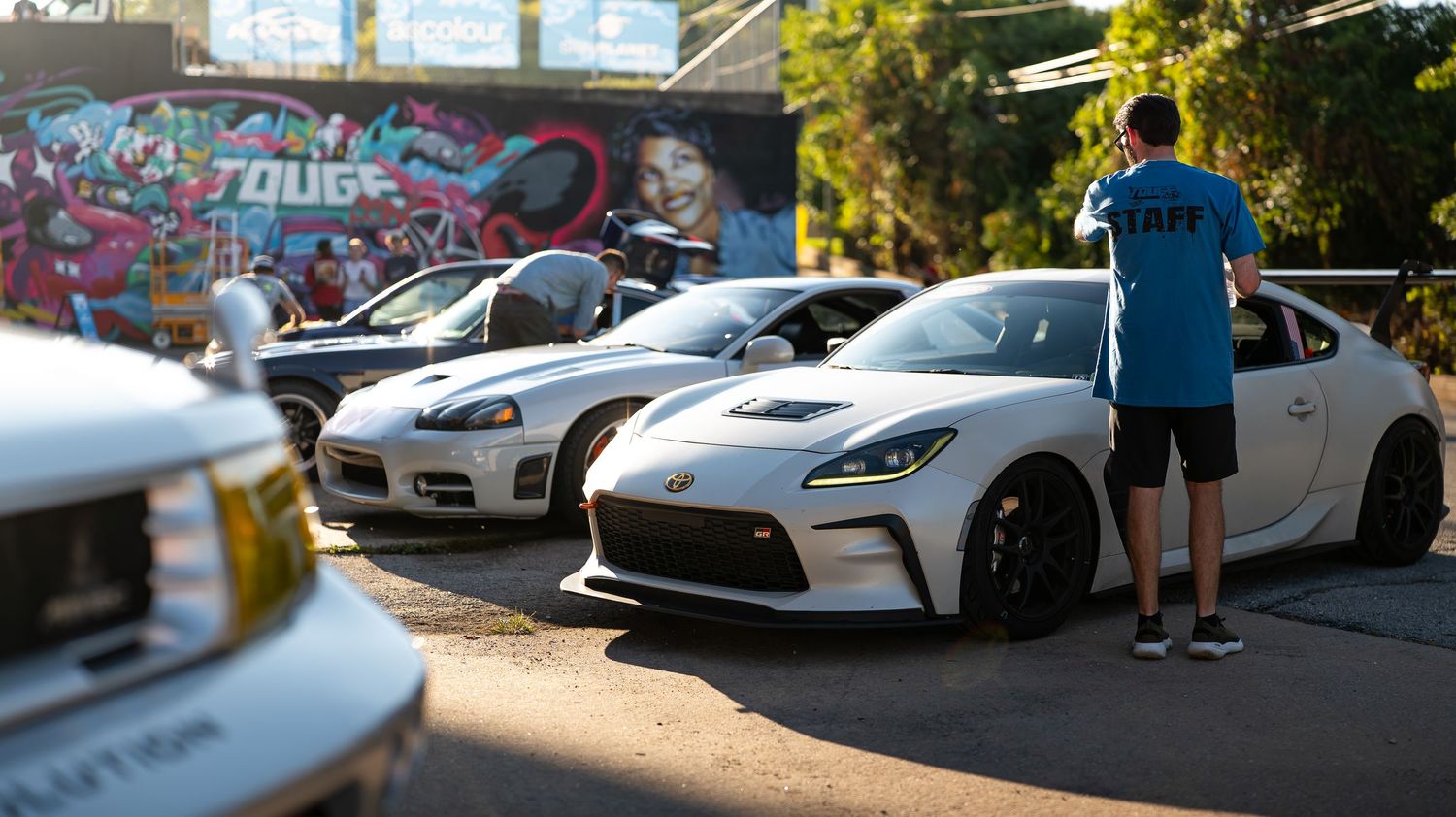 Row of luxury sports cars parked in a sunny outdoor lot.