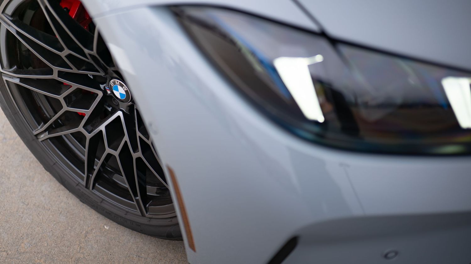 Close-up detail of BMW headlight and wheel on a white vehicle.