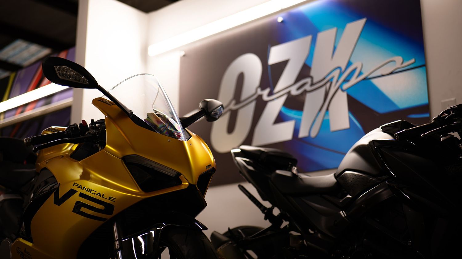 Custom motorcycles and vehicles displayed in a dimly lit showroom with blue lighting effects.