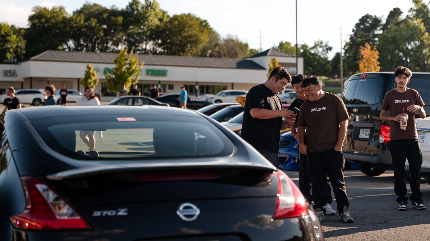Car enthusiasts gathered around modified Nissan at evening meet.