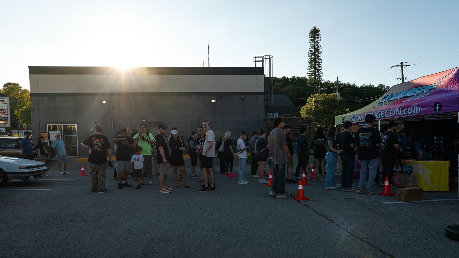 Panoramic view of a car meet gathering in a parking lot at dusk.