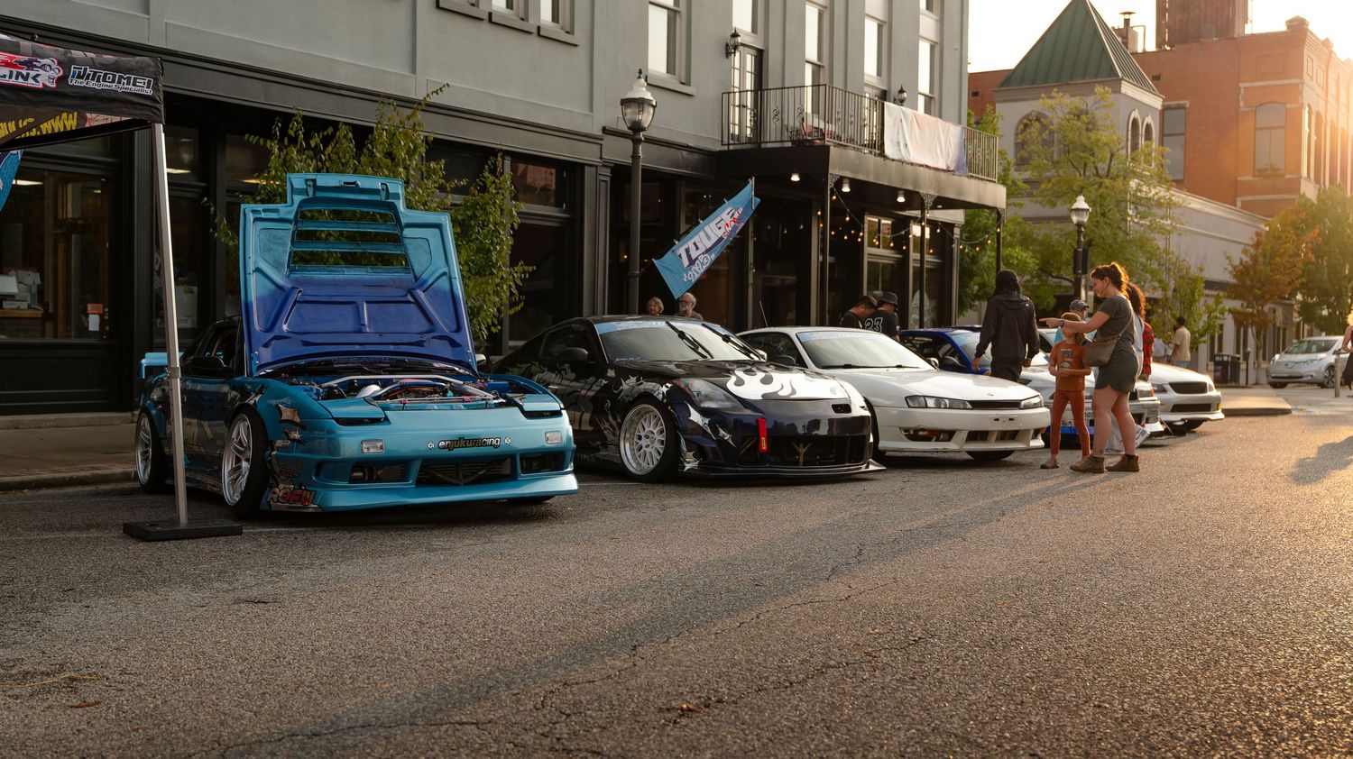 Wide angle street view showing historic buildings and cars in late afternoon light.