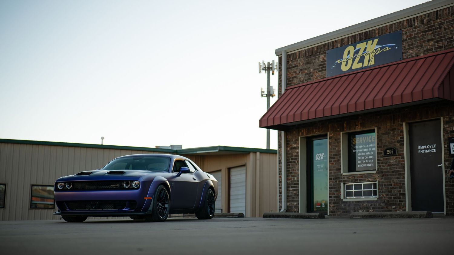Exterior view of a commercial building with vehicles parked outside at sunset.