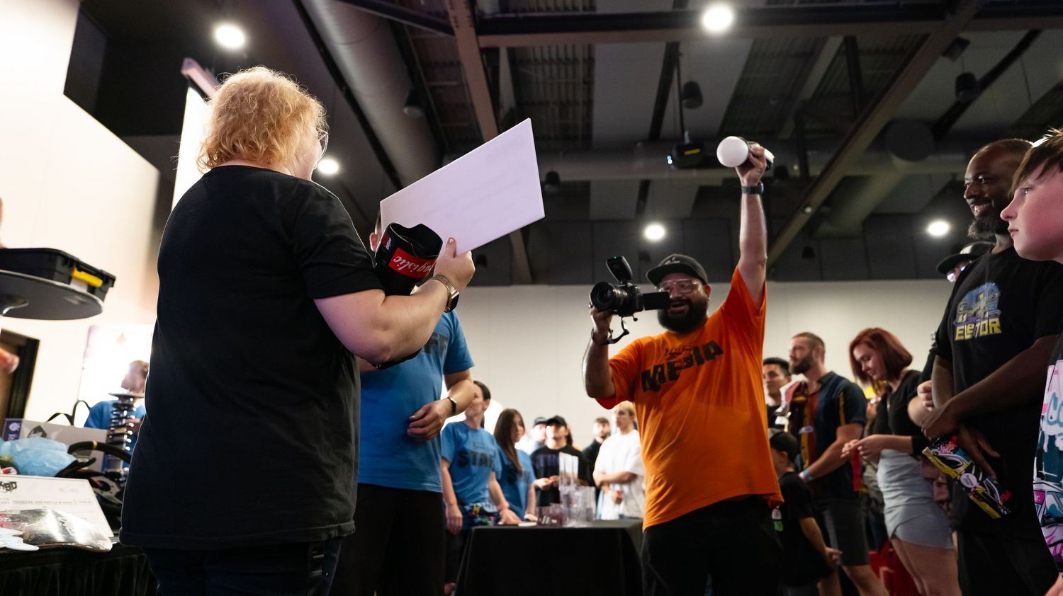 Large crowd of gaming fans gathered at an indoor convention event with colorful banners and displays.