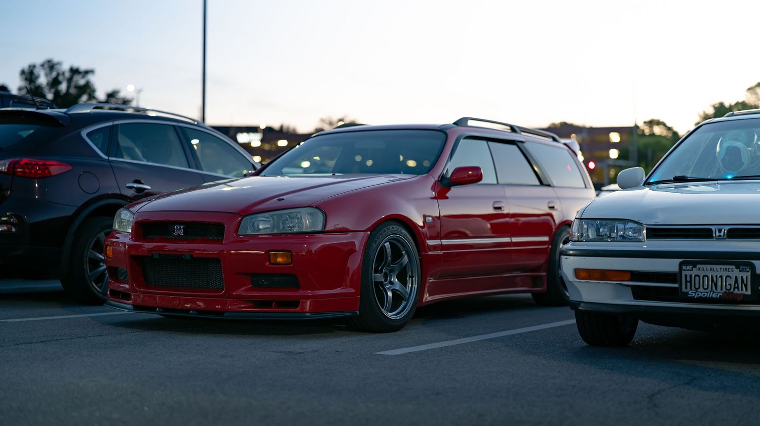 Custom lowered cars lined up at a sunset automotive gathering.