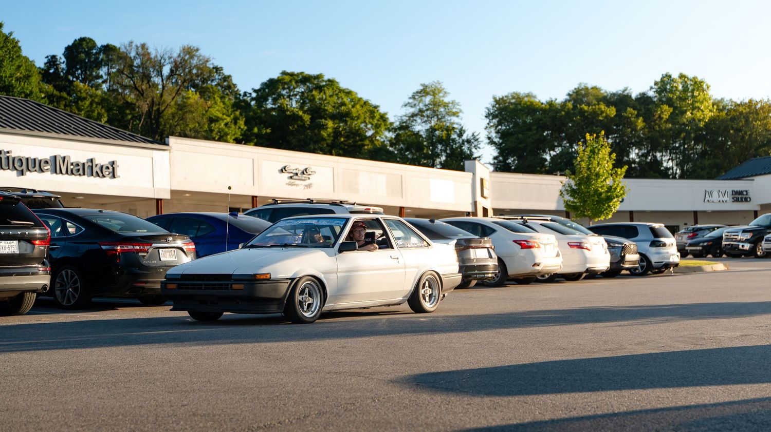 Wide angle view of a parking lot with cars lined up during daytime.