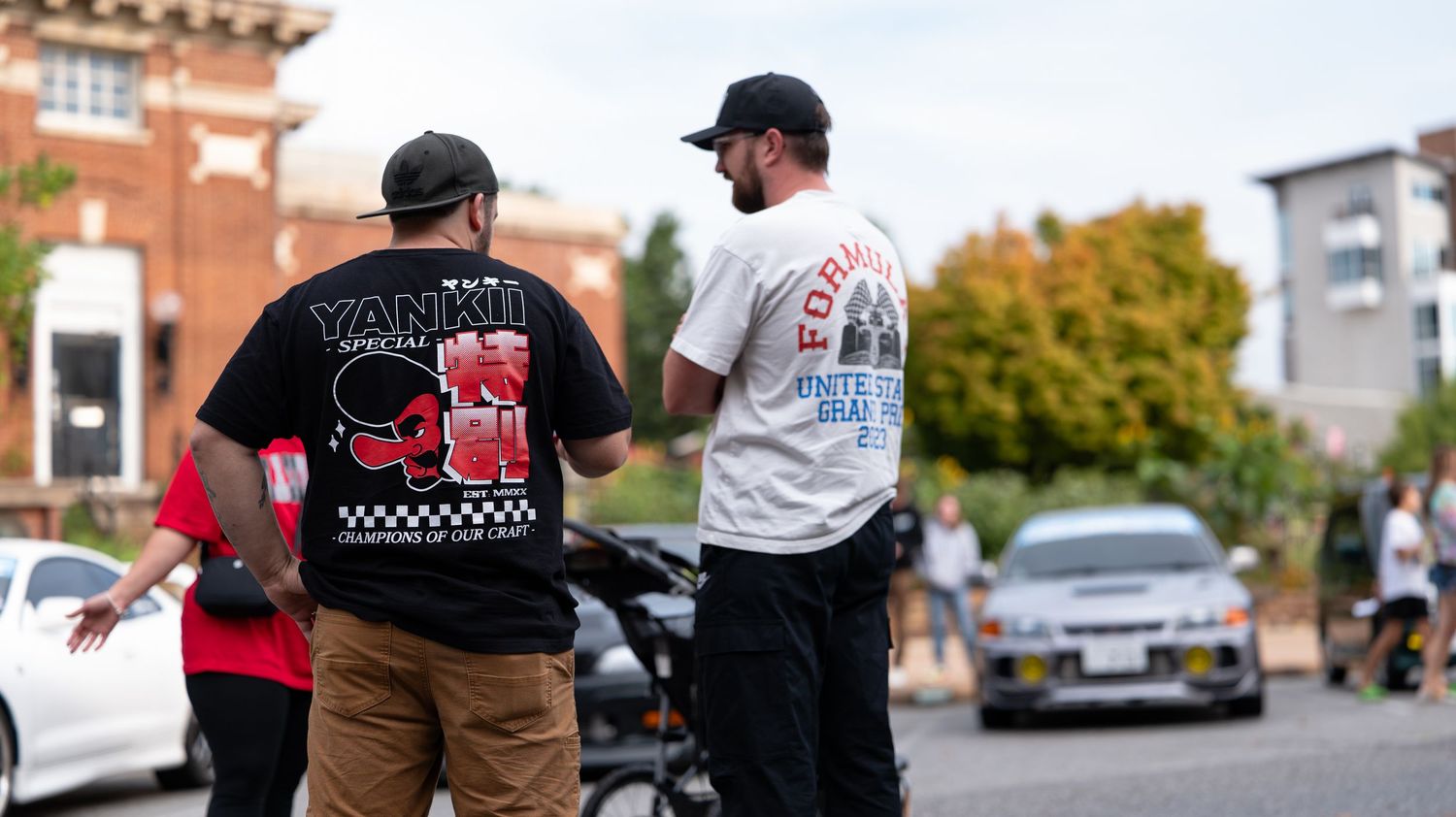 Car enthusiasts gathered around custom vehicles at an outdoor automotive event.