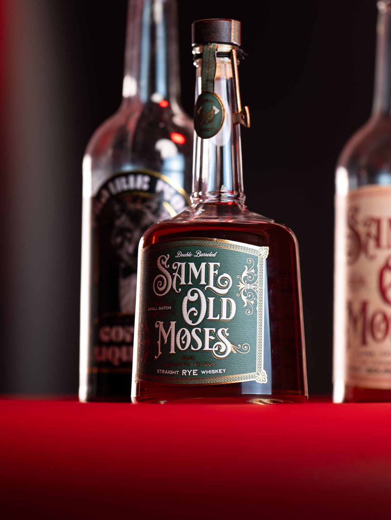 Close-up view of Saint Moses whiskey bottle with dark background and red velvet base.