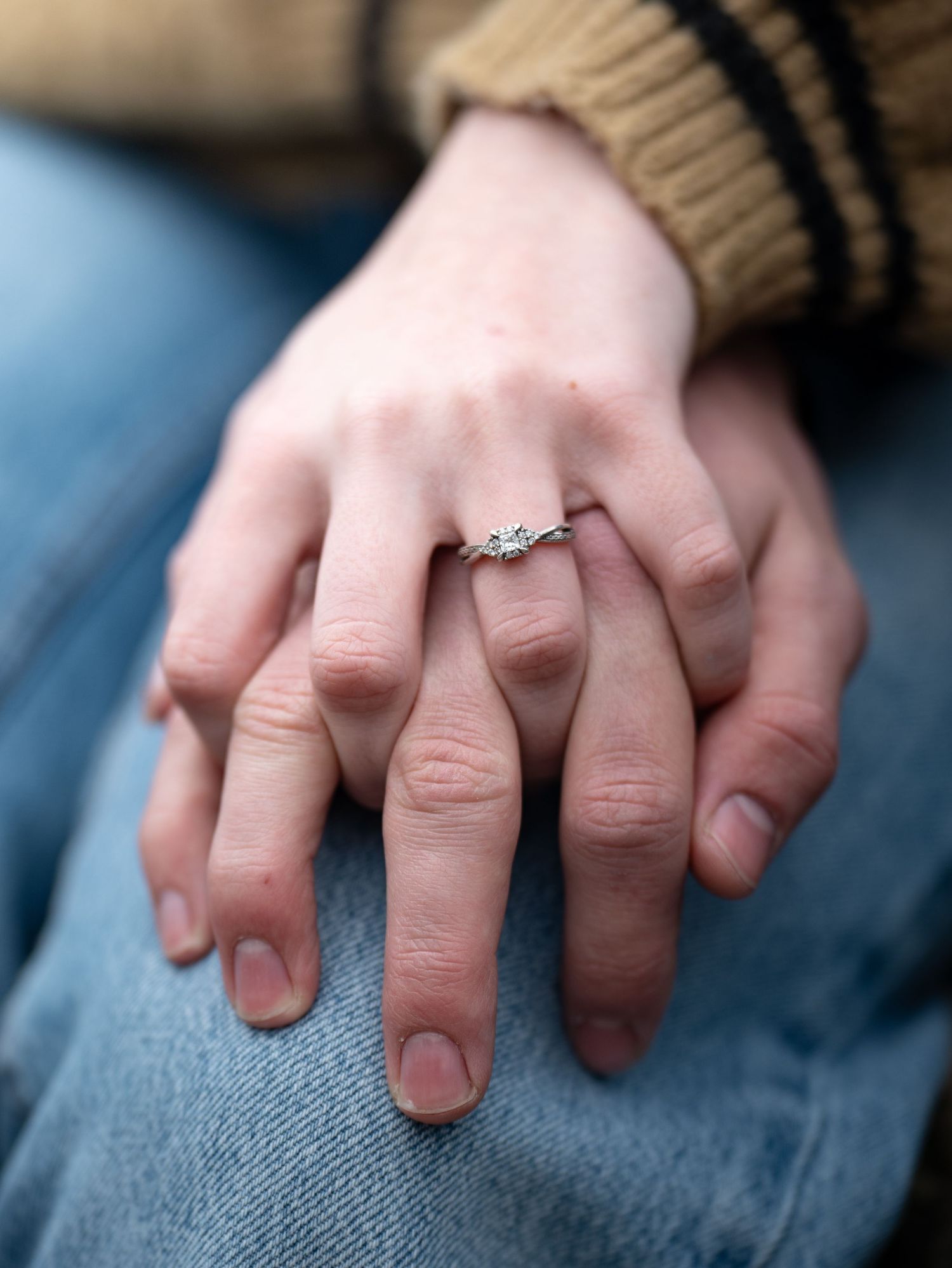 Close-up sequence showing a diamond engagement ring sparkling on a hand resting against denim fabric.