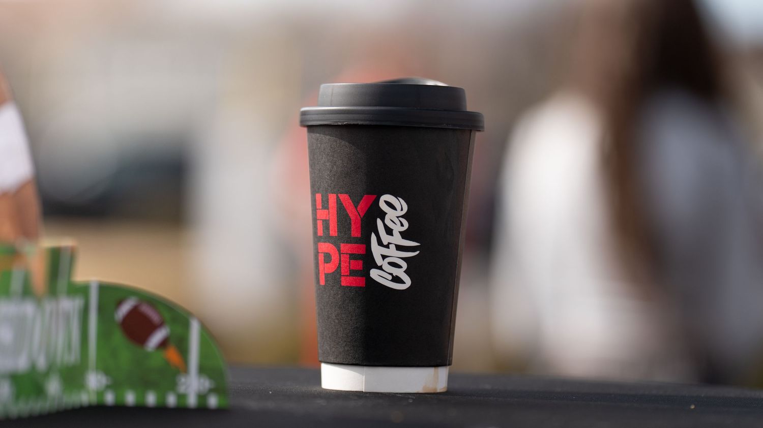 Multiple people holding coffee cups outside a building with red accents.
